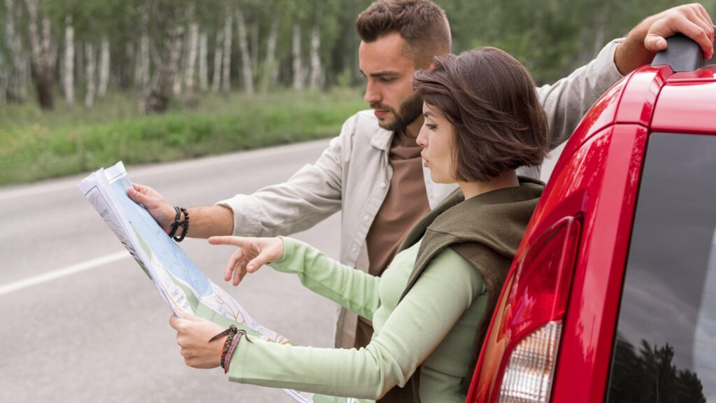 casal-jovem-em-pe-perto-carro-olhando-no-mapa